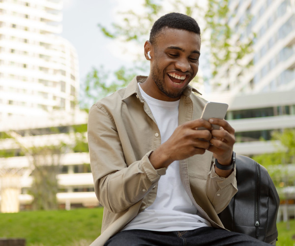 Joven interactuando con us celular al aire libre