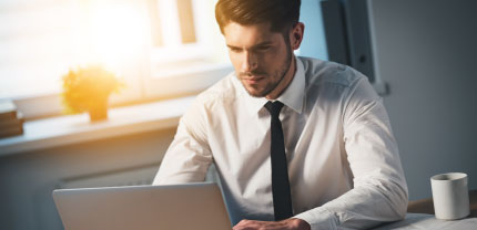 hombre de camisa blanca y corbata trabajando un computador